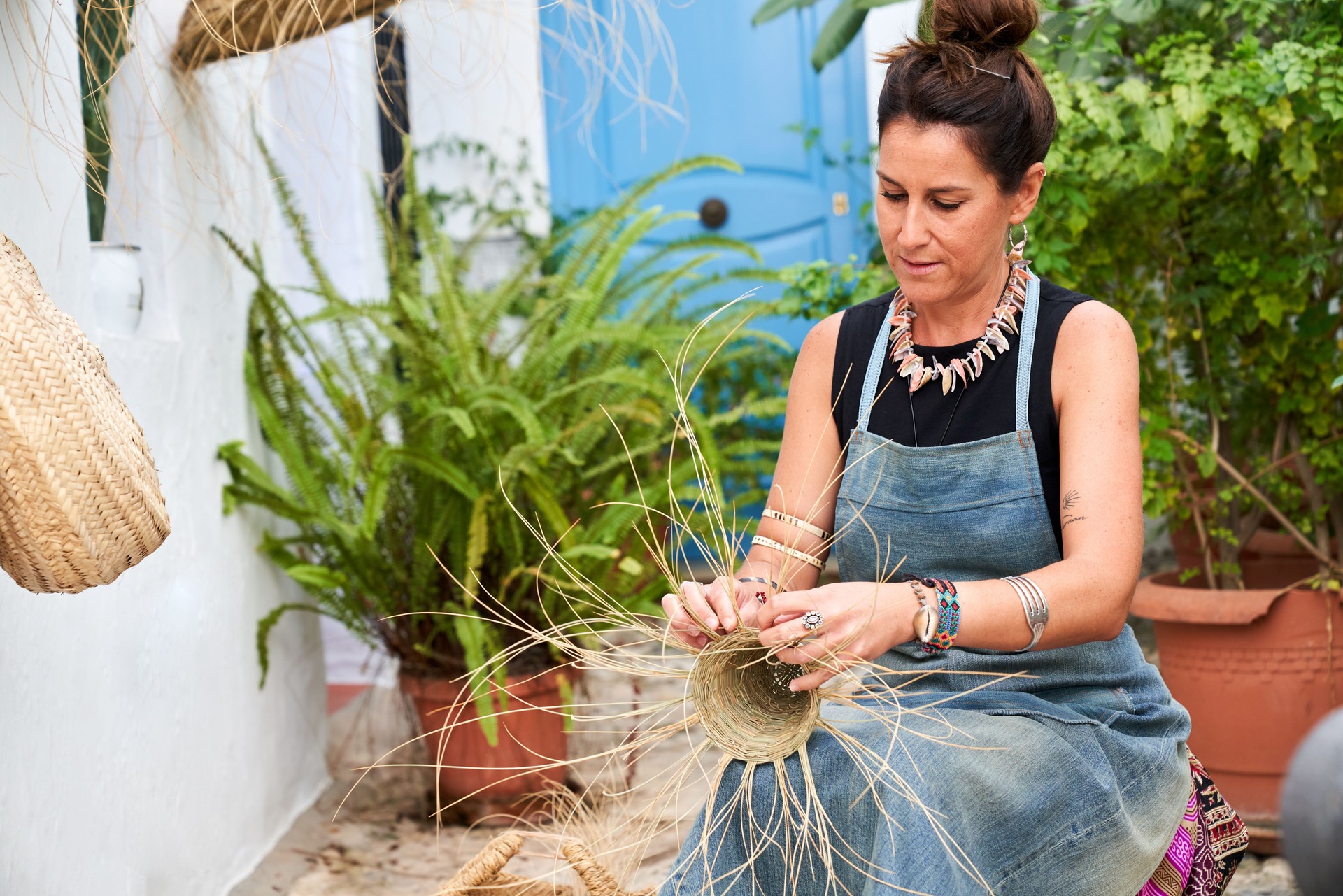 Middle-aged Hispanic woman weaving a basket with esparto fibers